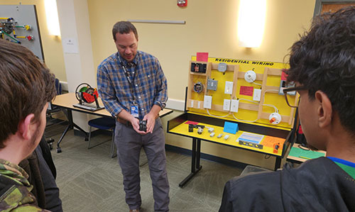 man showing electrical tubes to students